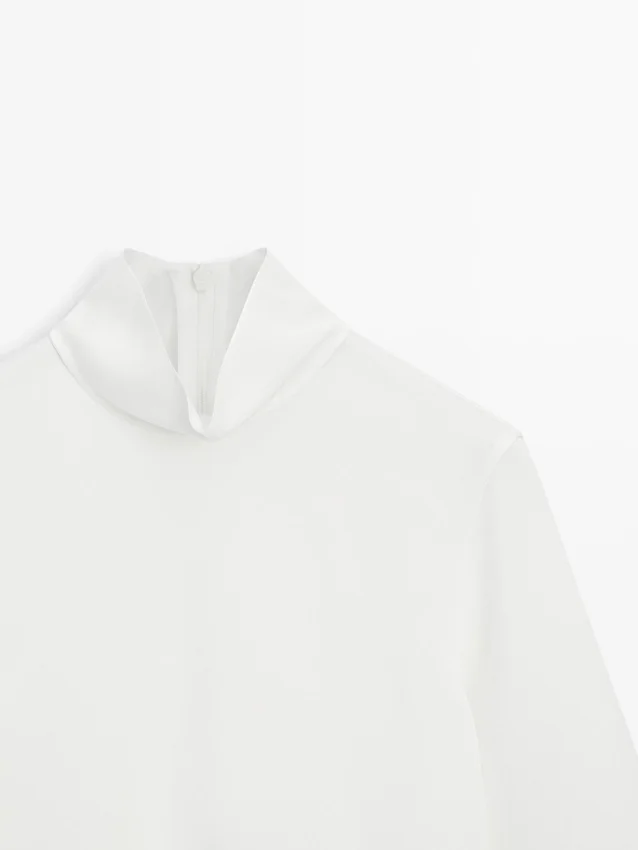 Camicetta a collo alto con dettaglio sull’orlo Camicetta a collo alto con dettaglio sull’orlo